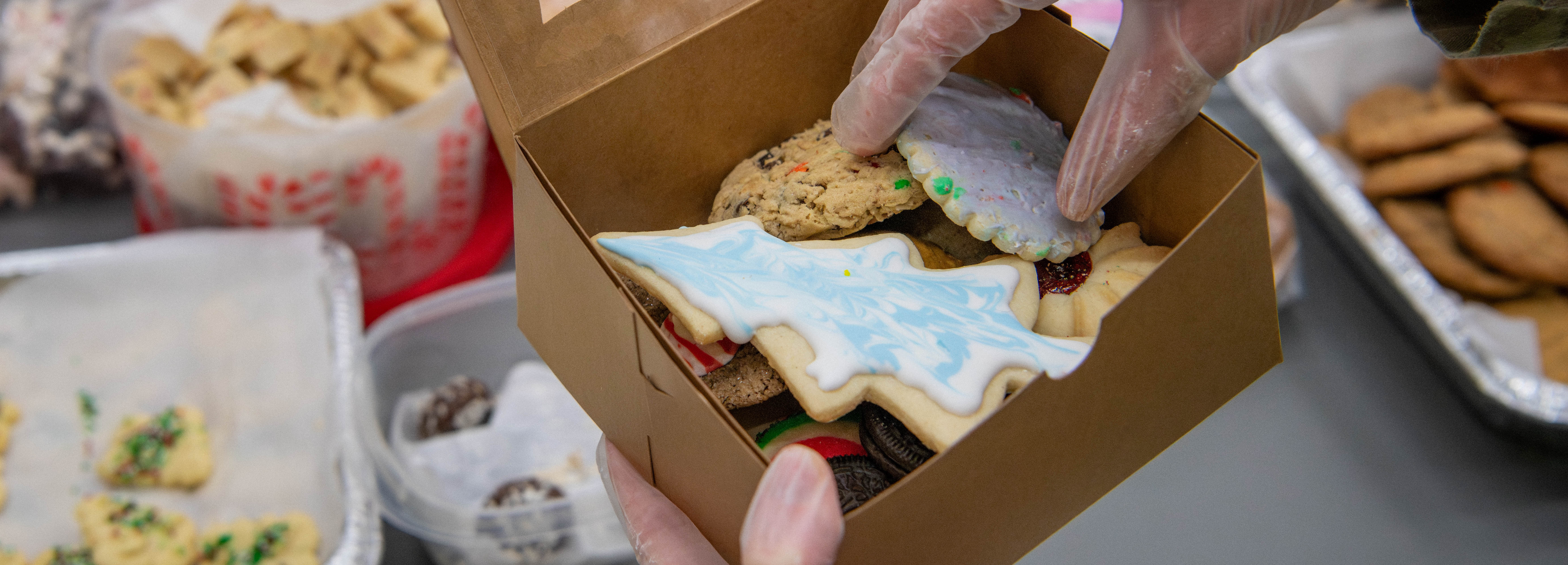 A photo of a person putting cookies in a box.