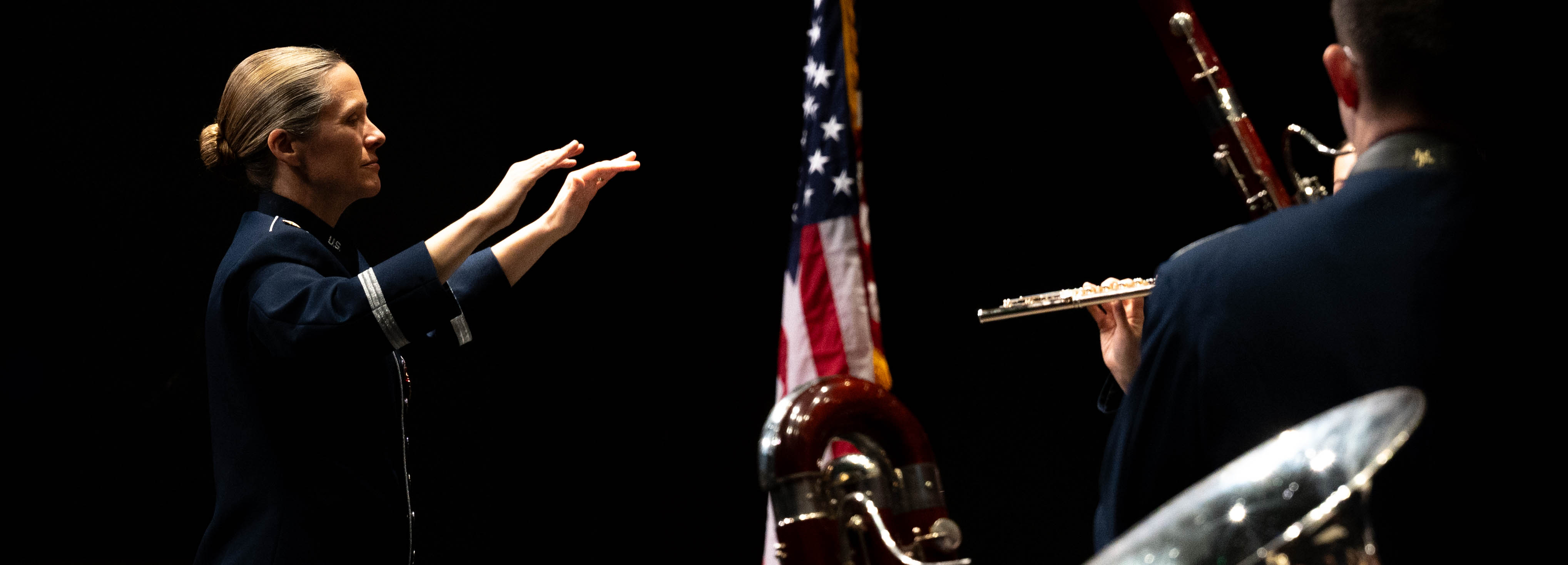 An Airman conducts a band on a stage.