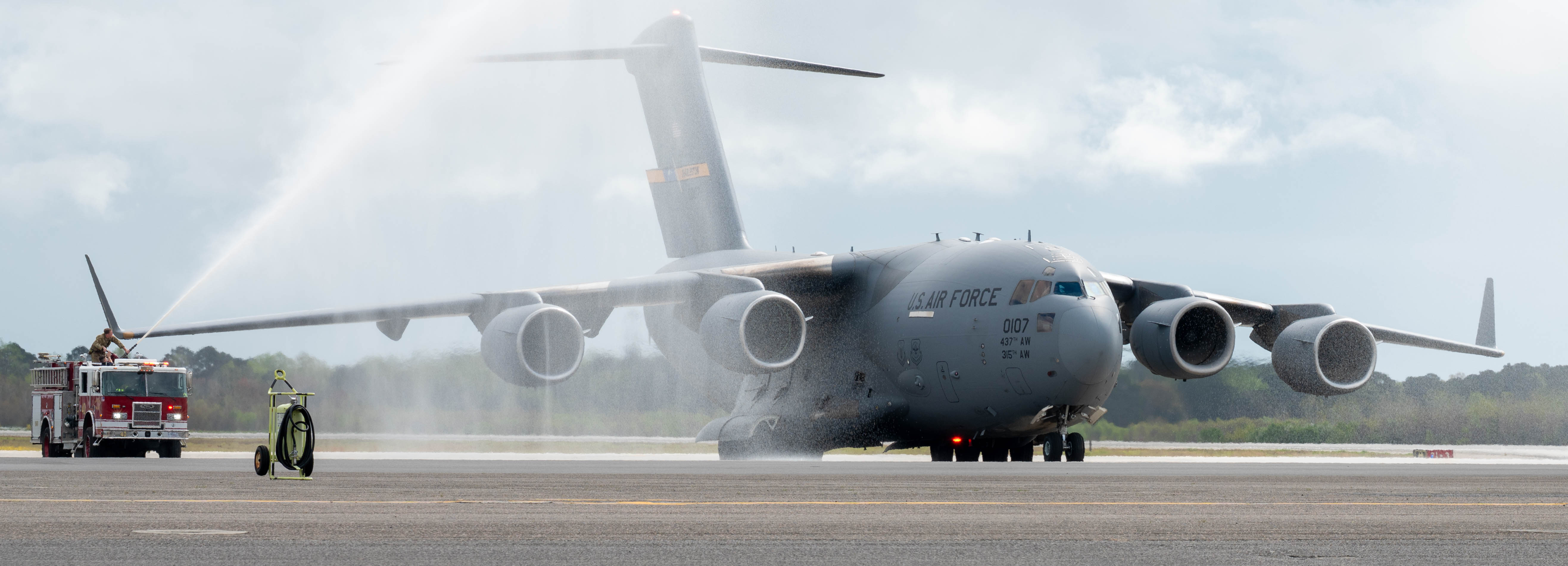A C-17 Globemaster III is sprayed by a firetruck