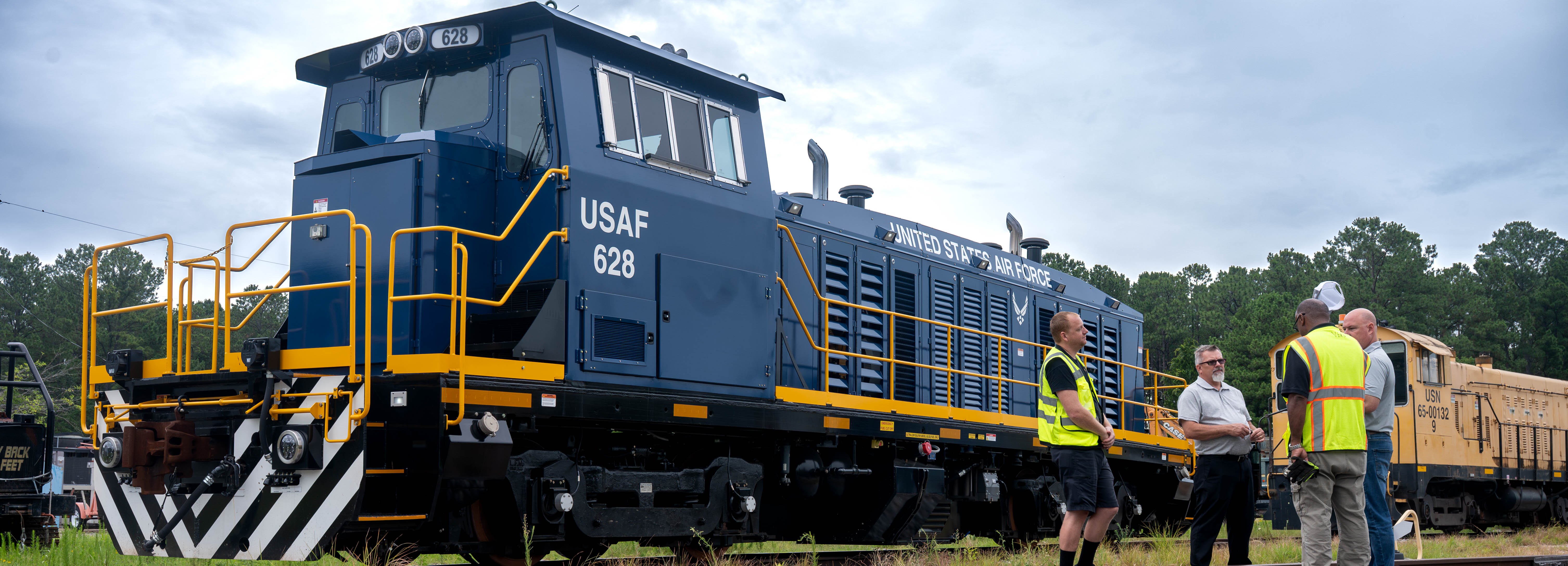 A photo of four people conversing in front of a locomotive.
