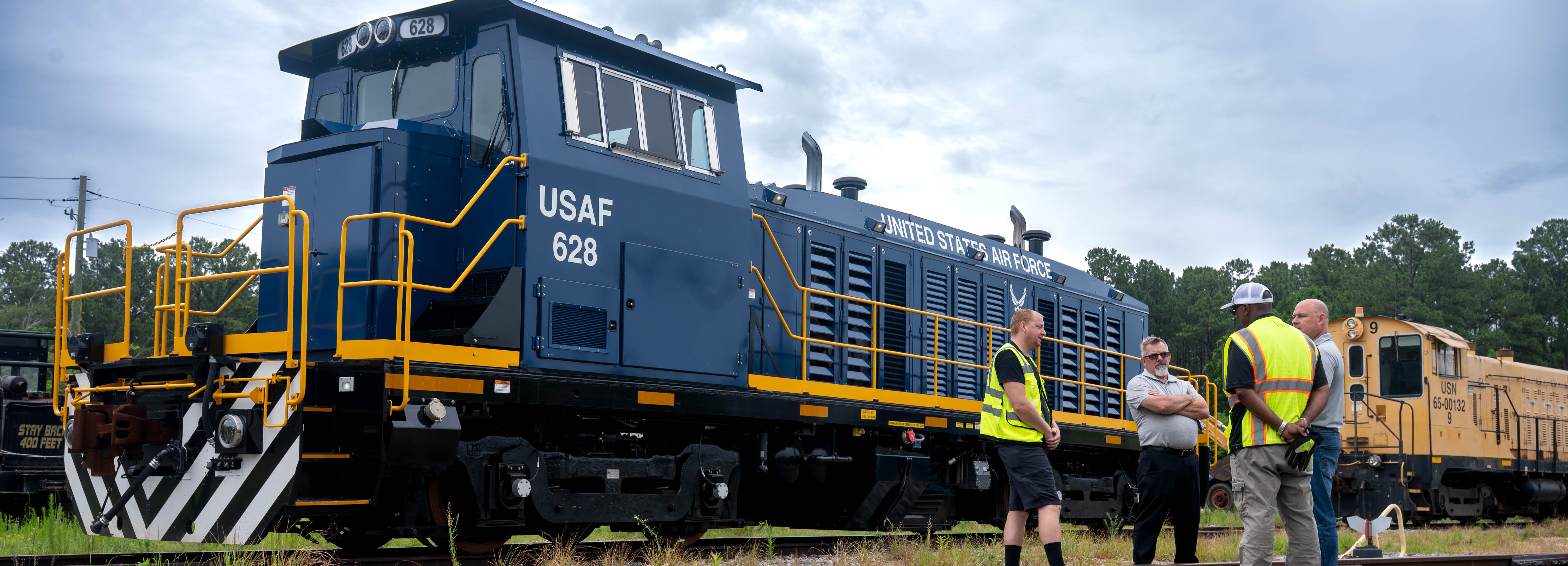A photo of four people conversing in front of a locomotive.