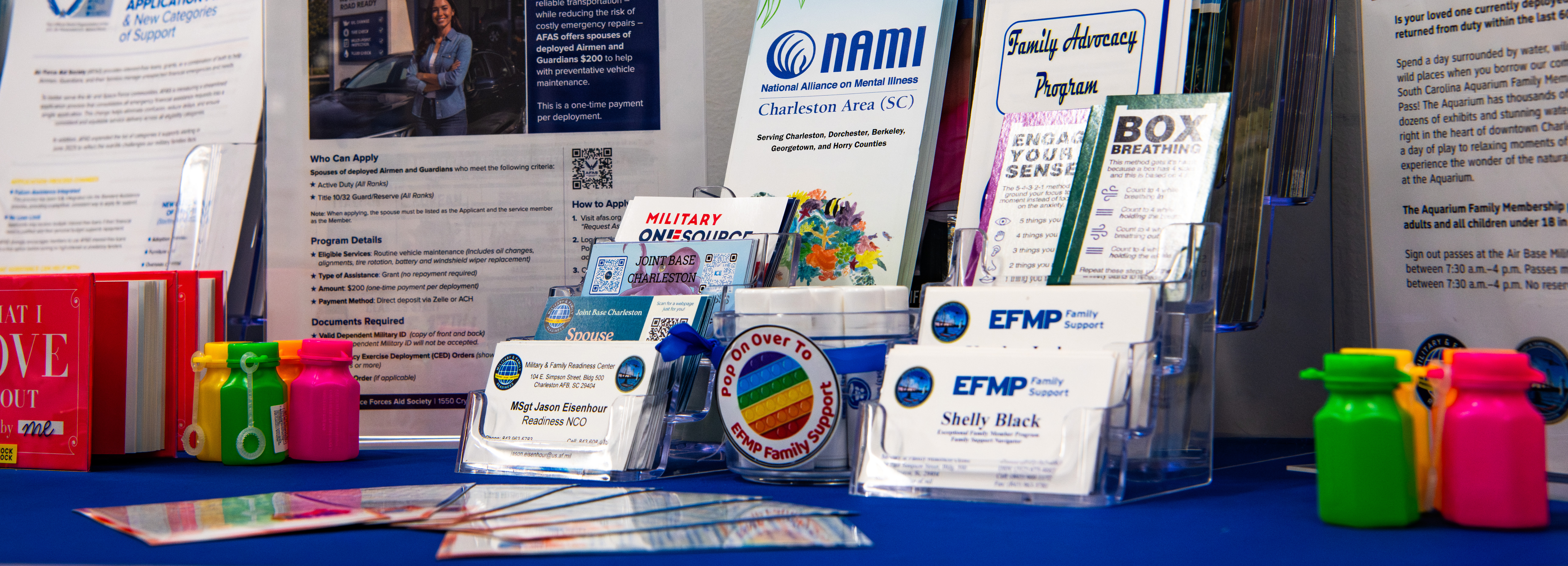Informational brochures and infographics of family support, deployment, and childcare programs are arranged on a table.